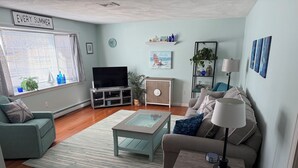 Ein Wohnzimmer mit Fernseher, Sofa, Couchtisch und Dekorationselementen.