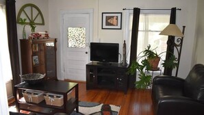 A living room with a television, a sofa, a cabinet, and a potted plant.