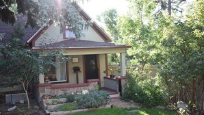 A house with a front porch, a small garden, and a wooden fence.
