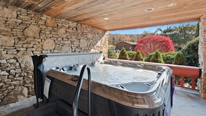 A stone wall, a hot tub, and a wooden ceiling. - Beautiful 6 Bed/4.5 Bath - Close To 7 Springs & Laurel Highlands Attractions (Champion)
