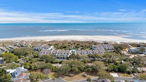 Uma área residencial costeira com imóveis à beira-mar, uma piscina e uma praia.