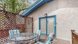Eine Terrasse mit rundem Tisch und gestreiften Stühlen, ein Holzboden und eine tür in blauem Rahmen.