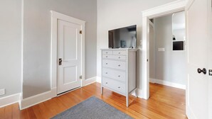 Ein Zimmer mit einer weißen Tür, einem grauen Teppich und einem weißen Schminktisch mit Schubladen.