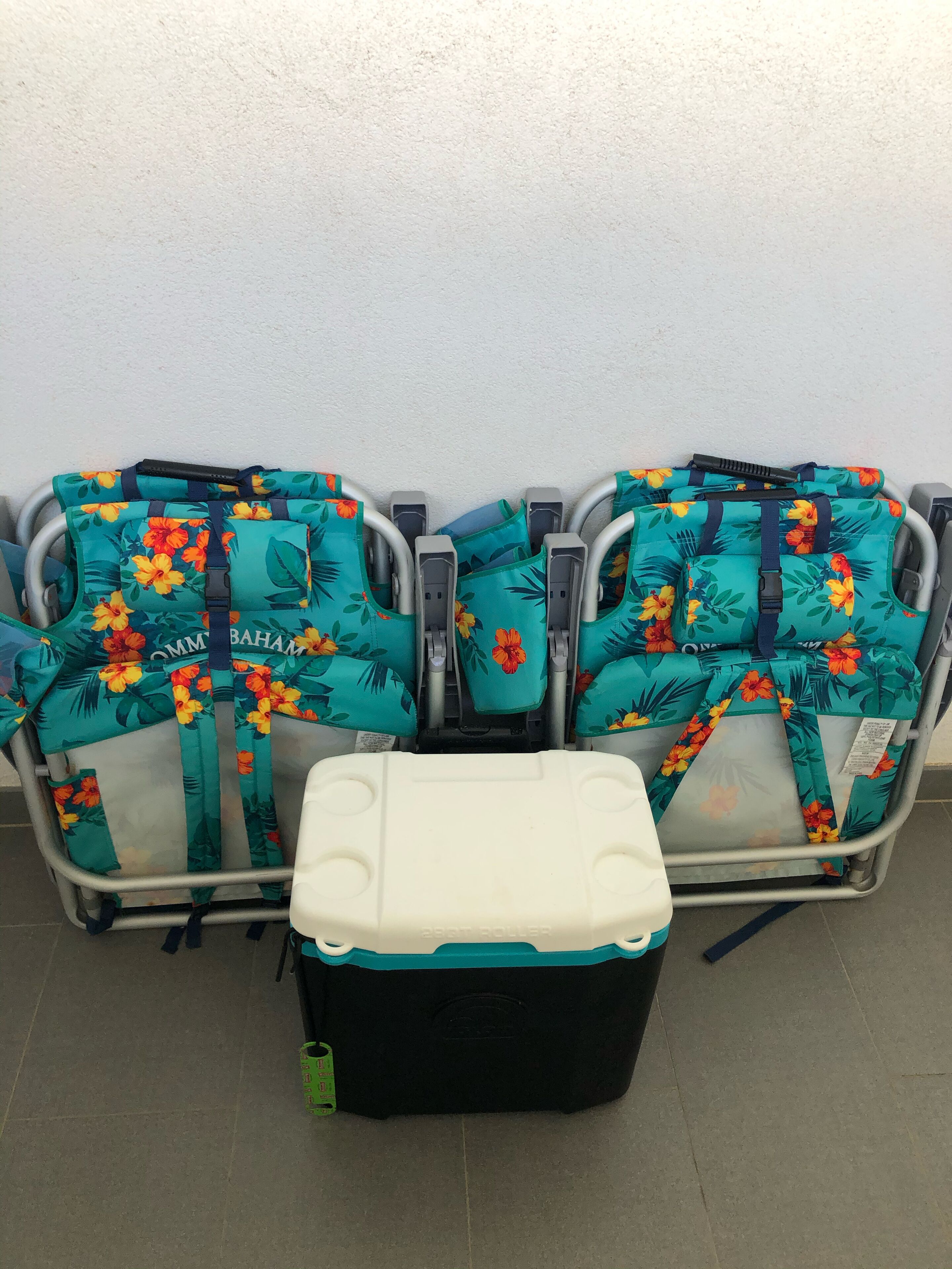 Une rangée de sièges d’aéroport recouverts d’un tissu à motifs floraux, avec un bac de rangement noir et blanc placé devant.