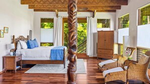 A room with a bed, wicker furniture, and a ceiling with geometric patterns. - Tiki Home - Unique Custom Home Steps to the Beach and Town (Hanalei)