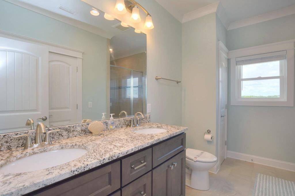 Une salle de bain avec deux lavabos, un grand miroir et des toilettes.