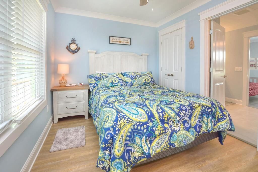 A bedroom with a bed, nightstand, and a door leading to another room.