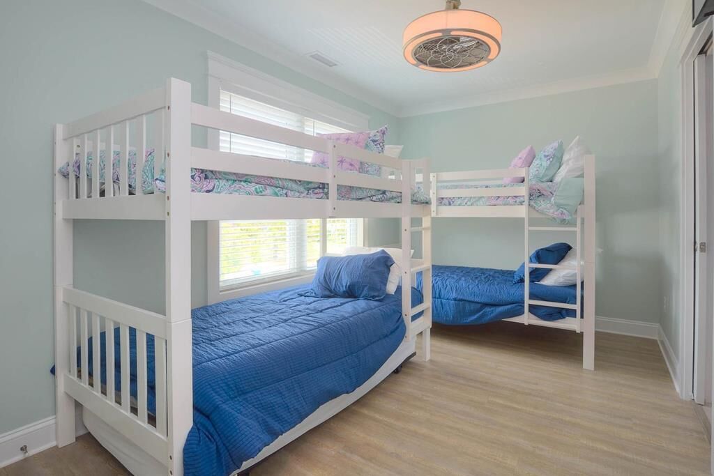 Ein Kinderzimmer mit Etagenbetten, einem Fenster und einem Deckenventilator.