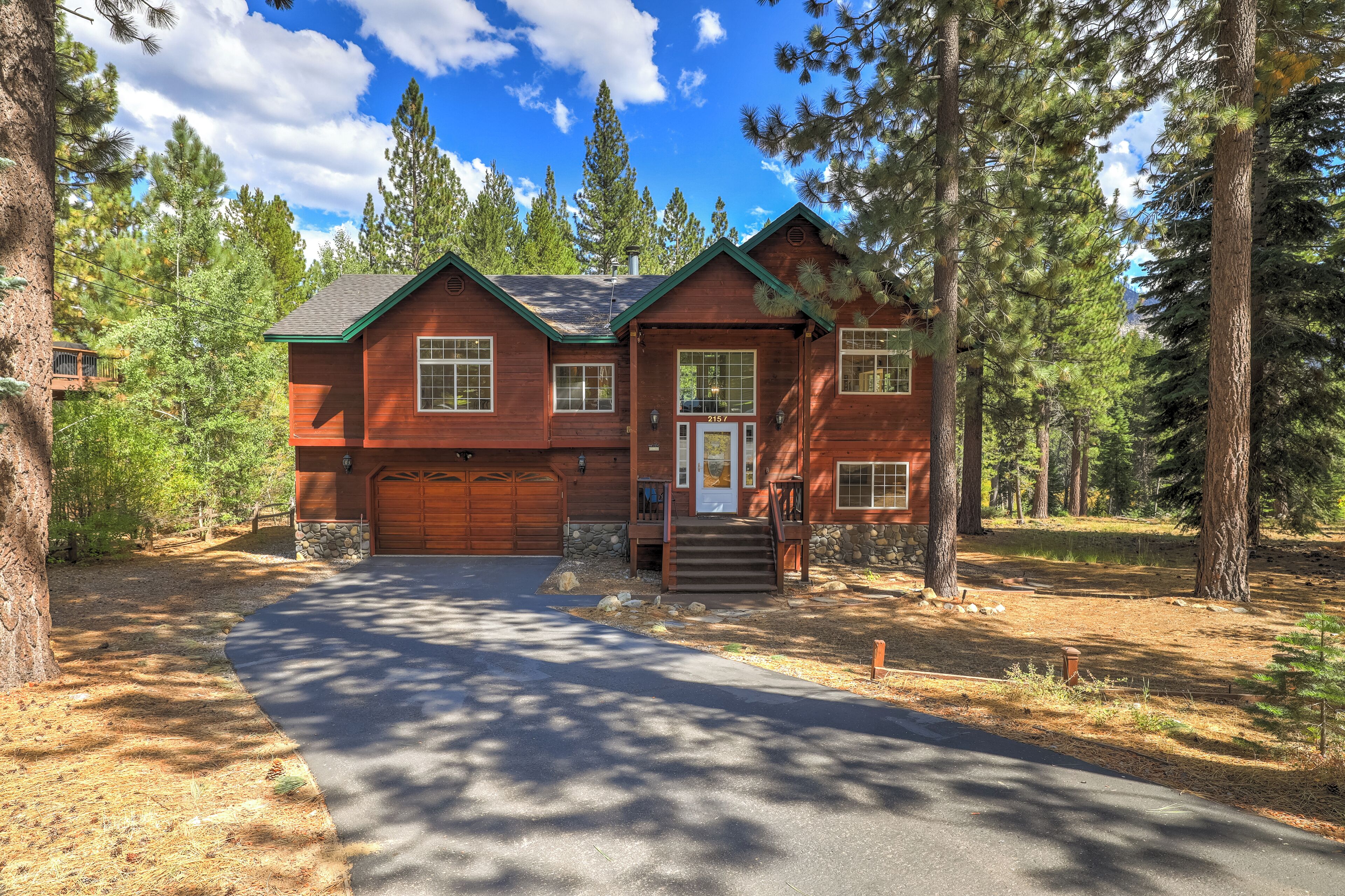 A two-story log cabin with a stone foundation, a garage, and a covered porch.