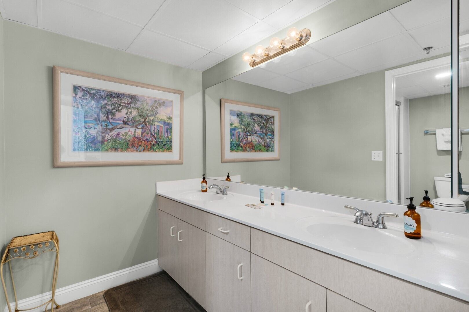 A bathroom with two sinks, a large mirror, and framed artwork on the walls.