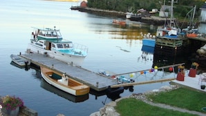 Un muelle con barcos, un espacio con césped y un pequeño edificio.