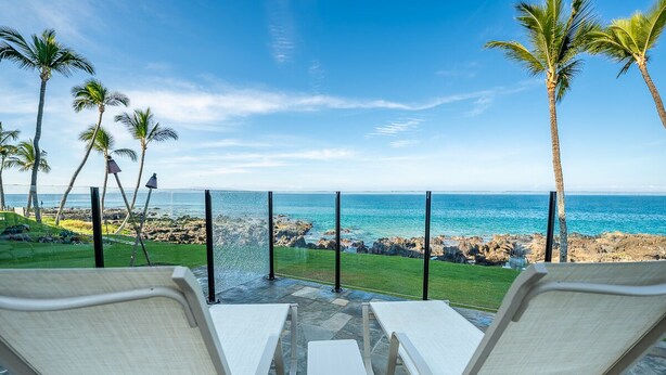A patio with two white lounge chairs facing a rocky coastline and the ocean. - 505 – Lovely Oceanfront 1/1.5 unit – great ocean view with A/C! (Kihei)