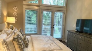 Un dormitorio con una cama grande, un aparador, un televisor y una ventana con persianas.