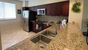 Una cocina moderna con encimeras de granito, electrodomésticos de acero inoxidable y armarios de madera oscura.