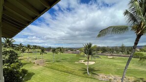 Un campo de golf con césped cuidado, hoyos de arena y palmeras.