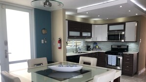 Eine moderne Küche mit einem Glastisch, Edelstahlgeräten und einer blauen Akzentwand.