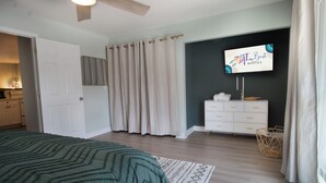 A bedroom with a bed, a dresser, a television, and a window with curtains. - 1Br/1Ba Close to Beach & Shops- Heron's Nest (Folly Beach)