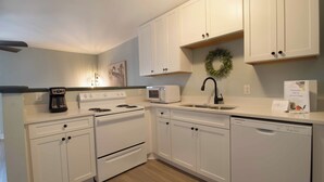 A modern kitchen with white cabinets, a microwave, stove, and dishwasher. - 1Br/1Ba Close to Beach & Shops- Heron's Nest (Folly Beach)