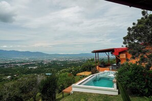 A modern house with a pool, surrounded by lush greenery and a view of a distant cityscape. - Heated Infinity Pool Villa, 6BR, 25Min SJO (Alajuela)