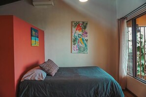 A room with a bed, a pillow, a wall with two paintings, and a window with a view of greenery. - Heated Infinity Pool Villa, 6BR, 25Min SJO (Alajuela)