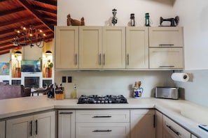 A kitchen with a gas stove, cabinets, and various kitchen utensils. - Heated Infinity Pool Villa, 6BR, 25Min SJO (Alajuela)