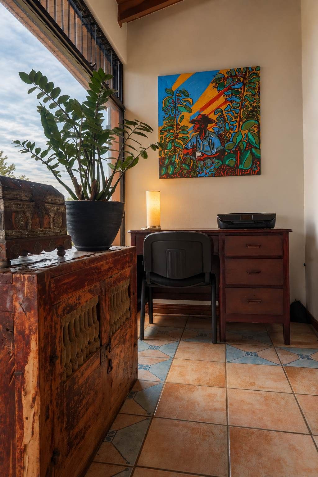 Une pièce comprenant un bureau, une chaise, une plante en pot et un tableau coloré accroché au mur.