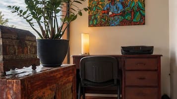 Une pièce comprenant un bureau, une chaise, une plante en pot et un tableau coloré accroché au mur.