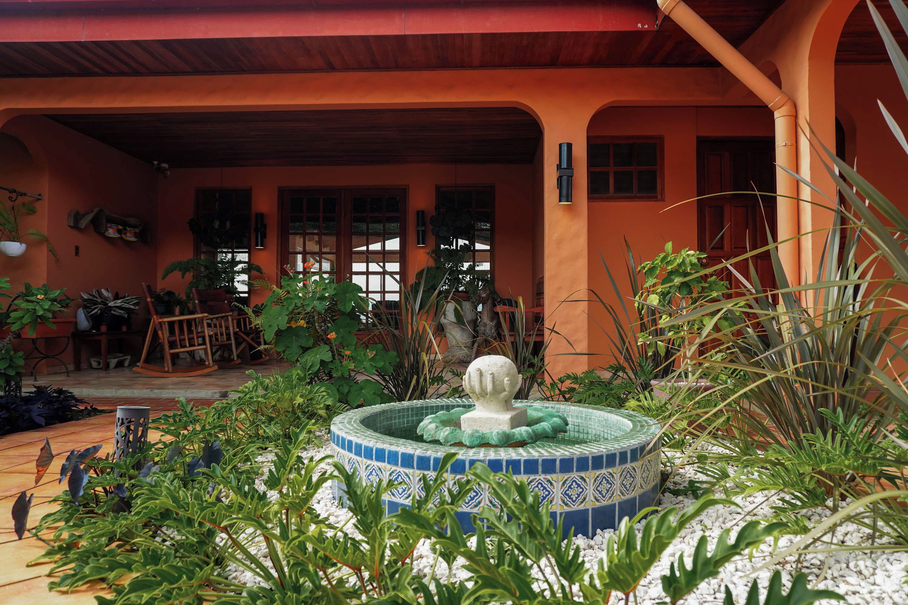 A courtyard with a fountain, potted plants, and a wooden deck.