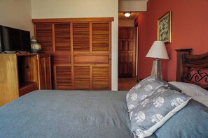 A bedroom with a bed, a wooden wardrobe, a television, and a lamp. - Heated Infinity Pool Villa, 6BR, 25Min SJO (Alajuela)