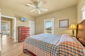 Wake up to natural light and coastal breezes in this inviting bedroom. The wood floors, ceiling fan, and cozy plaid bedding create a relaxed retreat, while your private balcony door opens to fresh air and peaceful surroundings. - Oceanview Rodanthe Home with Pool, Hot Tub, Elevator, Game Room, and Tiki Bar (Rodanthe)