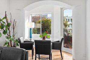 A modern room with a round table, four chairs, a potted plant, and a large window. - Located on Marina blvd  (San Francisco)