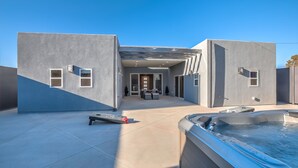 Une maison moderne dotée d’un patio, d’un jacuzzi et d’un espace salon extérieur abrité.
