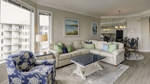 Ein Wohnzimmer mit einer Couch, Sesseln, einem Couchtisch und Blick auf ein Gebäude.
