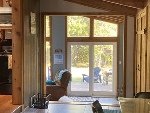 A room with a large sliding glass door leading to an outdoor deck. There is a brown chair and a small table inside the room.