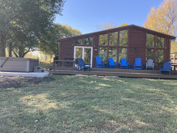 A wooden cabin with a covered porch, outdoor seating, and a small deck area.