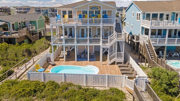 A multi-story beachfront house with a pool, multiple decks, and outdoor seating areas. - Luxury Oceanfront Retreat: Concierge Beach Tent Service, Private Pool & Elevator (Holden Beach)