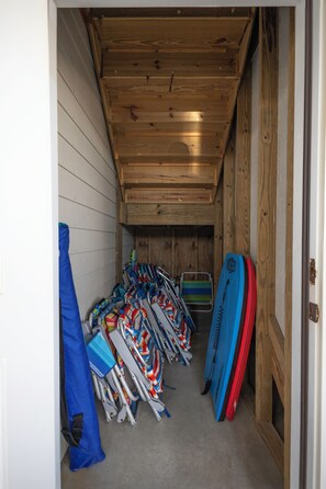 A narrow hallway with wooden walls and ceiling, lined with rows of skis and snowboards. - Luxury Oceanfront Retreat: Concierge Beach Tent Service, Private Pool & Elevator (Holden Beach)