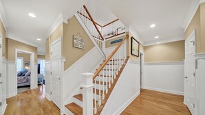 A staircase with white railings and wooden steps leading to a landing. - Luxury Oceanfront Retreat: Concierge Beach Tent Service, Private Pool & Elevator (Holden Beach)