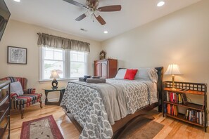 A bedroom with a bed, a chair, a bookshelf, a window, and a ceiling fan. - Big, Beautiful & Beachside Bliss - Sleeps 10! (Hampton)