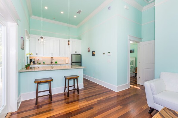A spacious kitchen with white cabinets, a central island, and wooden flooring.