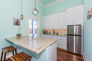 A kitchen with white cabinets, a stainless steel refrigerator, and a granite countertop.