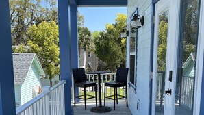 Een overdekt terras met een tafel en stoelen, een welkomstmat en uitzicht op de omgeving.
