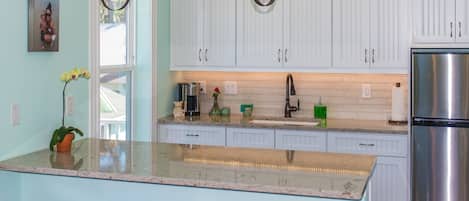 A kitchen with white cabinets, a stainless steel refrigerator, and a granite countertop.