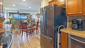 Una cuina amb un frigorífic Samsung, armaris de fusta, una cafetera Keurig i una zona de dinar amb vista a l'oceà.
