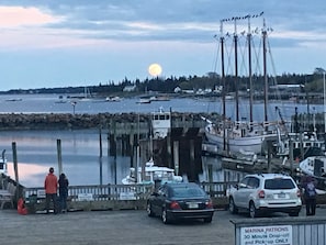 A marina with boats docked, a sign for marina patrons, and a sunset in the background.