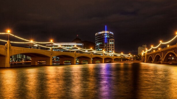 A nighttime view of a bridge with illuminated lights and a modern building in the background. - SLEEPS 6 Beautiful, Fully Furnished Condo - Great Price, Perfect Location! (Tempe)