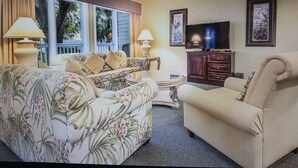 A living room with a sofa, armchairs, a coffee table, a TV, and a ceiling fan.