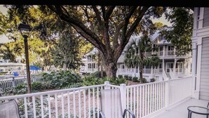 A balcony with white railings, a table, and two chairs.