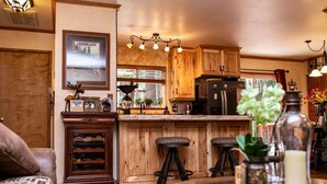 Una cocina con armarios de madera, un refrigerador y una zona de comedor con taburetes.