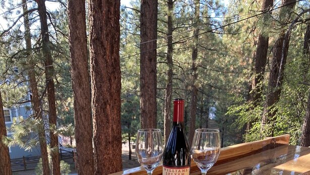 A wooden deck with a bottle of Williams Selyem 2018 Pinot Noir and two glasses on a wooden table. - Perfect Family Getaway,  One Light to Snow Summit, Bear Mountain and Shopping (Big Bear Lake)